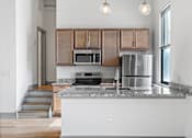 Thumbnail 1 of 20 - A kitchen with a stainless steel refrigerator, microwave, and oven.