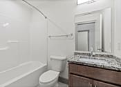 Thumbnail 10 of 20 - A white bathroom with a toilet, sink, and bathtub.