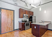 Thumbnail 13 of 20 - A kitchen with wooden floors and a refrigerator, microwave, oven, and sink.
