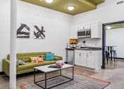 Thumbnail 10 of 10 - A living room with a green couch and a coffee table.