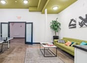 Thumbnail 9 of 10 - A room with a ping pong table and a green couch.