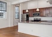 Thumbnail 3 of 10 - A kitchen with wooden cabinets and a stainless steel refrigerator.
