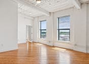 Thumbnail 6 of 10 - A large empty room with wooden floors and white walls.