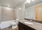 Thumbnail 11 of 13 - A bathroom with a white toilet and a white bathtub.