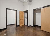 Thumbnail 9 of 13 - A room with a white wall and a door on the left and a white fridge in the middle.