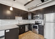Thumbnail 2 of 13 - A kitchen with black cabinets and stainless steel appliances.