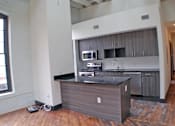 Thumbnail 4 of 5 - A kitchen island with a black countertop and wooden cabinets.