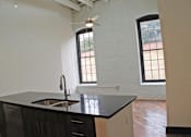 Thumbnail 3 of 5 - A kitchen with a black counter top and a window.