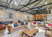 Thumbnail 5 of 22 - A large, open-plan living area with a variety of seating options and a high ceiling with exposed beams.