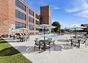 Thumbnail 3 of 22 - A pool area with chairs and umbrellas in front of a brick building.