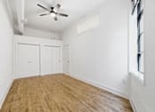 Thumbnail 18 of 22 - A room with a ceiling fan and wooden flooring.