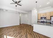 Thumbnail 11 of 22 - A kitchen with a fan on the ceiling and wooden floors.