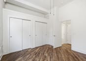 Thumbnail 20 of 22 - A room with white walls and wooden floors with four white doors.