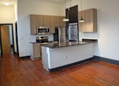 Thumbnail 2 of 7 - A kitchen with wooden floors and white walls.