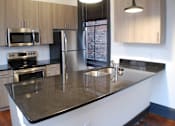 Thumbnail 4 of 7 - A kitchen with a granite counter top and stainless steel appliances.