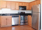 Thumbnail 3 of 8 - A kitchen with wooden cabinets and stainless steel appliances.