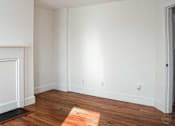 Thumbnail 7 of 8 - A room with wooden floors and white walls.