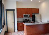 Thumbnail 6 of 6 - A kitchen with wooden cabinets and a counter.