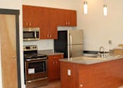 Thumbnail 5 of 6 - A kitchen with wooden cabinets and a refrigerator.