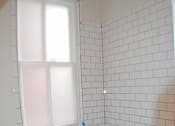 Thumbnail 17 of 22 - A white toilet sits next to a bathtub in a bathroom with white tiles.