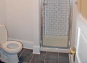 Thumbnail 14 of 22 - A white toilet in a bathroom with a glass shower door.