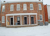 Thumbnail 9 of 22 - A red brick house with a white door and windows.