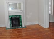 Thumbnail 12 of 22 - A fireplace with a green border sits in a room with wooden floors.