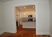 Thumbnail 6 of 22 - A kitchen with white cabinets and a black countertop is visible through an open doorway.