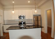Thumbnail 5 of 22 - A kitchen with white cabinets and a black countertop.