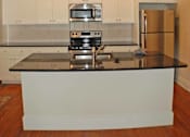 Thumbnail 4 of 22 - A kitchen with a black counter top and white cabinets.