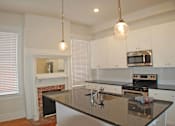 Thumbnail 3 of 22 - A kitchen with a black counter top and white cabinets.