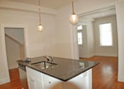 Thumbnail 2 of 22 - A kitchen with a black counter top and white cabinets.