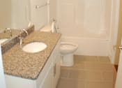 Thumbnail 6 of 8 - A white bathroom with a sink, toilet and shower.