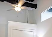 Thumbnail 18 of 20 - A bed with a white comforter and a blue pillow is in a room with a ceiling fan.