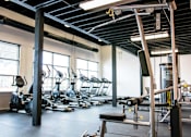 Thumbnail 19 of 22 - A gym with a variety of equipment including treadmills, weights, and exercise machines.