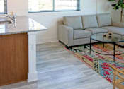 Thumbnail 6 of 22 - A modern kitchen with a wooden island and a grey couch.