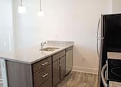 Thumbnail 12 of 13 - A kitchen with a black refrigerator and a sink with a granite countertop.