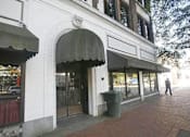 Thumbnail 13 of 13 - A white building with a black awning and a man walking in front.