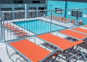 Thumbnail 23 of 24 - A pool with orange sun loungers and a blue sky.