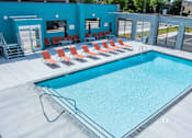 Thumbnail 2 of 19 - A swimming pool with red chairs around it.