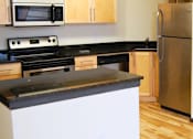 Thumbnail 2 of 7 - A kitchen with a stove, microwave, and refrigerator.