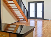 Thumbnail 4 of 7 - A wooden staircase with a black railing leads to a white door.