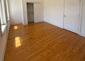 Thumbnail 5 of 8 - A room with a ceiling fan and wooden flooring.