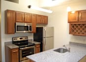 Thumbnail 1 of 6 - A kitchen with a stove, refrigerator, and microwave.