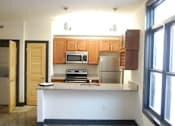 Thumbnail 2 of 6 - A kitchen with a white counter and wooden cabinets.