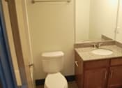 Thumbnail 6 of 6 - A white toilet is in a bathroom with a granite counter top.