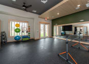 Thumbnail 26 of 39 - a home gym with a television and exercise equipment at the enclave at woodbridge apartments in sugar at The Bend Arbordale, Williamsburg, Virginia