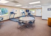 Thumbnail 10 of 15 - a gym with a table and chairs and a treadmill