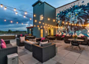 Thumbnail 30 of 34 - a patio with tables and chairs and a mural on the side of a building  at West Line Flats, Lakewood, CO, 80214