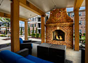 Thumbnail 33 of 37 - a patio with a brick fireplace and furniture at Annandale Apartment Homes, Murfreesboro